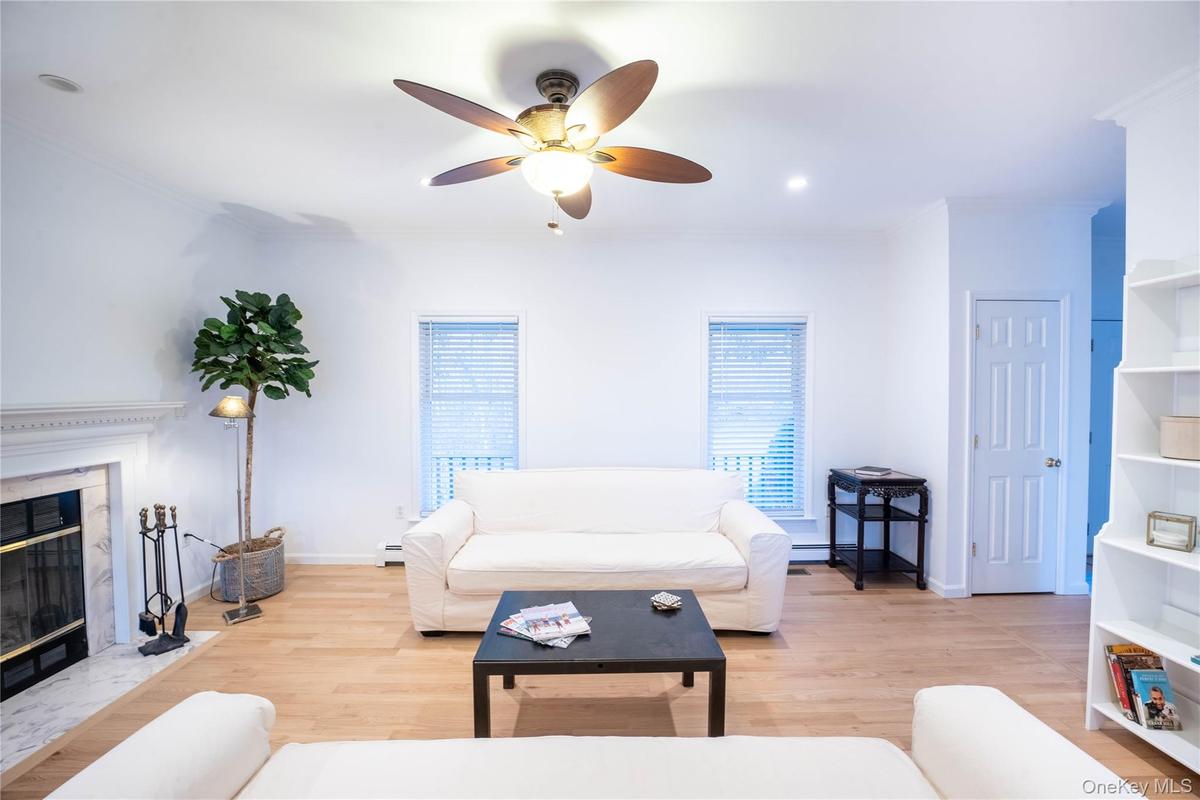 Living area with light wood-type flooring, a baseboard radiator, a fireplace, and a wealth of natural light