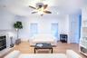 Living area with light wood-type flooring, a baseboard radiator, a fireplace, and a wealth of natural light