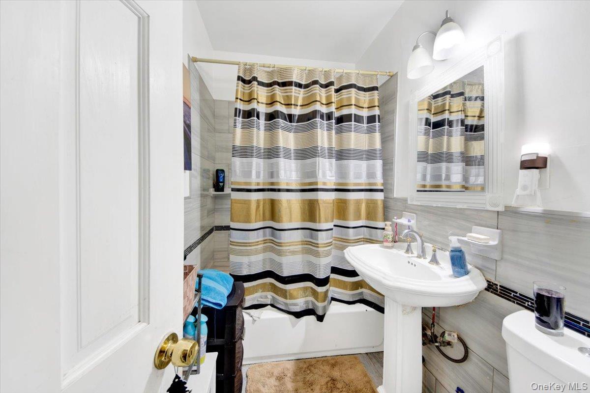 Full bathroom with tile walls and shower / bath combination with curtain