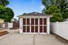 Detached garage with dark panel doors, a concrete driveway, and a white privacy fence