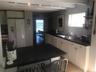 Kitchen with white refrigerator with ice dispenser, a sink, dishwasher, dark countertops, and beamed ceiling