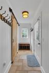 Mudroom featuring ornamental molding and a barn door