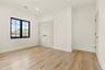 Bright interior space featuring a multi-pane window with black trim, light wood-finish flooring, white walls, recessed ceiling lighting, and white dou