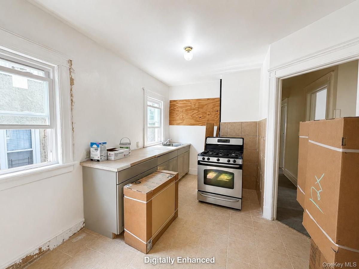 Unfinished Kitchen featuring a stainless steel range, tile flooring, light-colored countertops, and two windows providing natural illumination