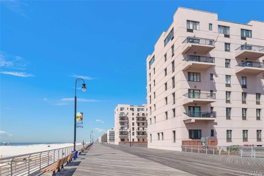 View of apartment building / complex featuring view of water and beach