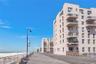 View of apartment building / complex featuring view of water and beach