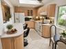 Eat-in-kitchen featuring light wood cabinetry, white appliances, speckled countertops, and white tile flooringDigitally staged eat-in-kitchen showing 