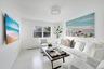 Living room with view of local beach, a baseboard heating unit, and light wood-style floors