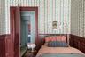 Bedroom featuring wainscoting, wallpapered walls, and a decorative wall