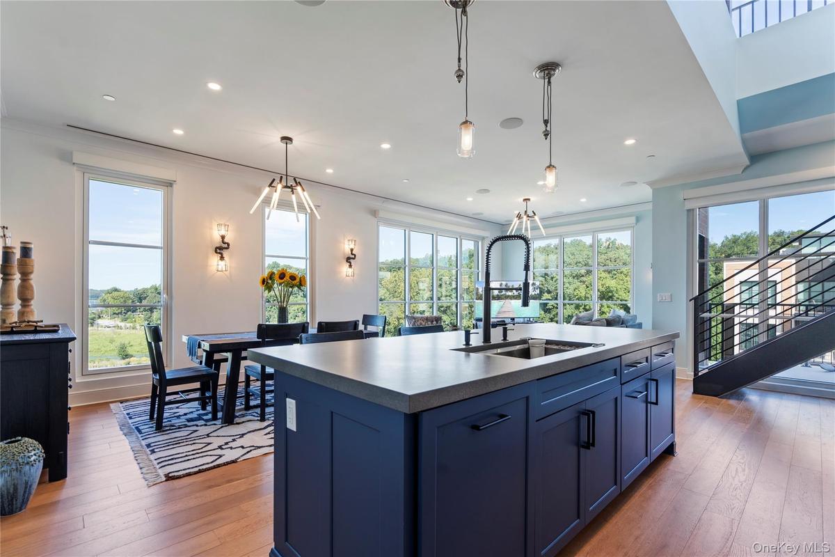 Kitchen with blue cabinets with natural light, a kitchen island with sink, light flooring, and recessed lighting