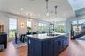 Kitchen with blue cabinets with natural light, a kitchen island with sink, light flooring, and recessed lighting