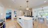 Kitchen featuring stainless steel appliances, white cabinetry, hanging light fixtures, and radiator