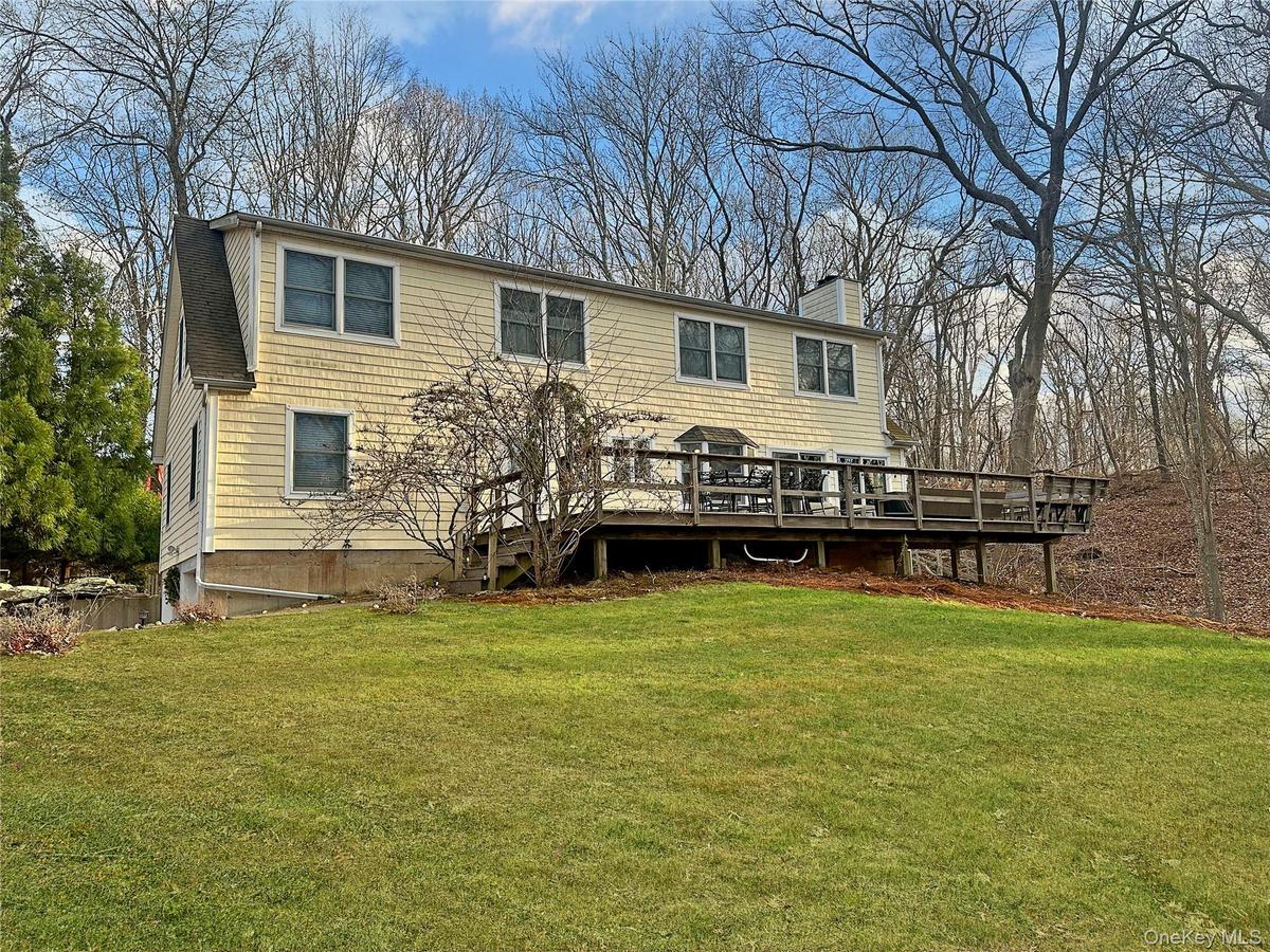 Rear view of house with a yard, a wooden deck, and a chimney