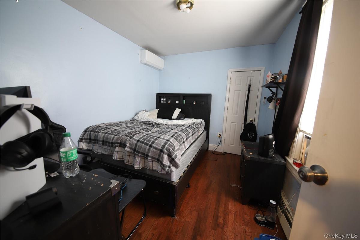 Bedroom with wood finished floors and an AC wall unit