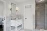 Full bath with a shower stall, vanity, tile walls, and wainscoting