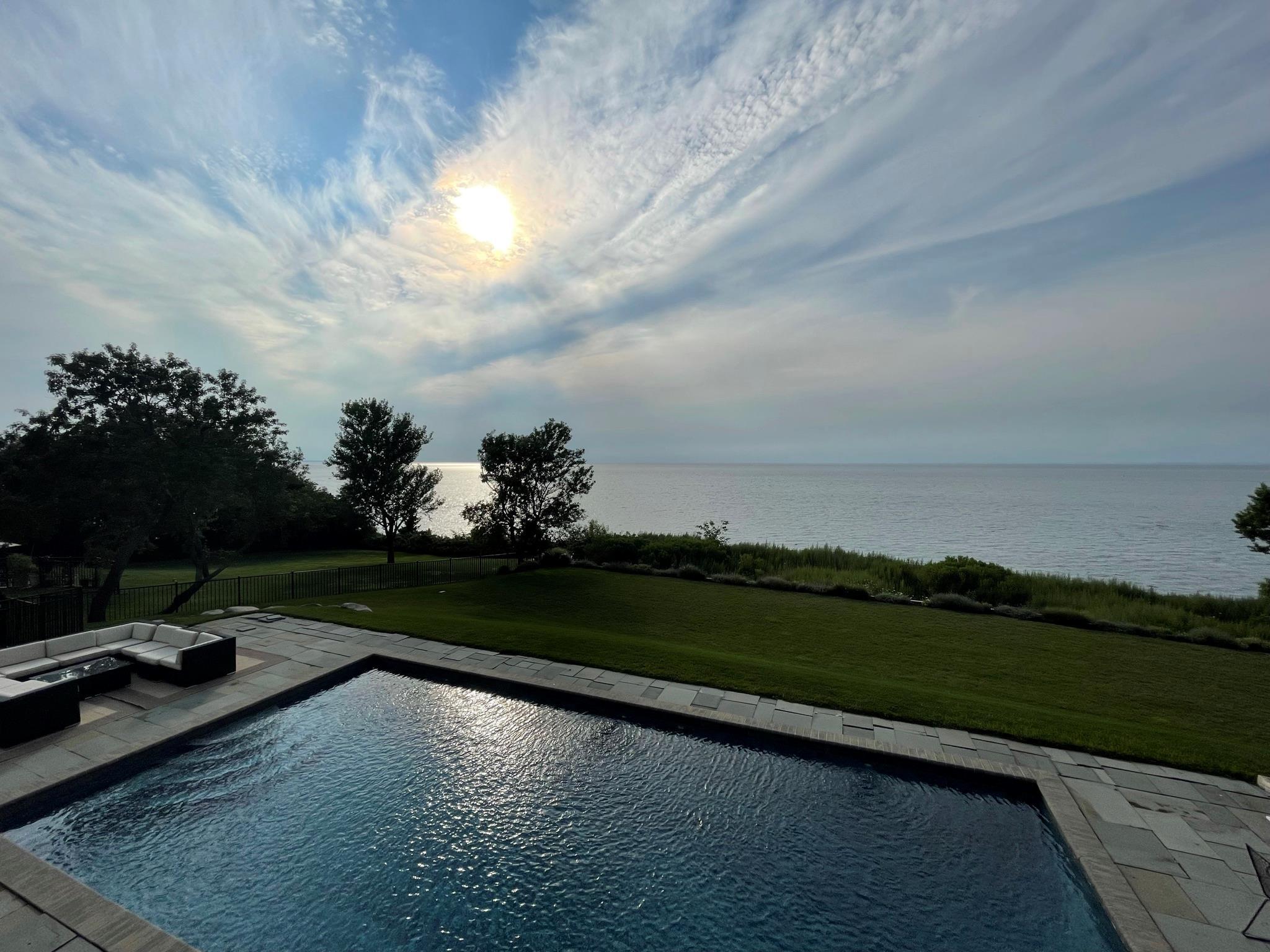View of pool featuring a water view, a patio area, and a lawn