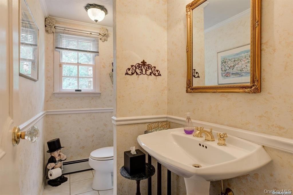 Bathroom featuring crown molding, wallpapered walls, tile patterned flooring, and baseboard heating