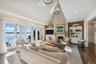 Living area with built in shelves, a stone fireplace, high vaulted ceiling, dark wood-type flooring, and recessed lighting
