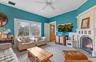 Living room featuring visible vents, a brick fireplace, a ceiling fan, carpet, and crown molding