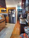 Kitchen with stainless steel appliances, glass insert cabinets, light countertops, granite floors, and brown cabinets