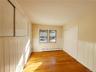 Empty room featuring light wood-style floors, a wainscoted wall, and a baseboard radiator