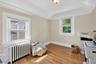 Bedroom with radiator heating unit, light wood-style flooring, and lofted ceiling