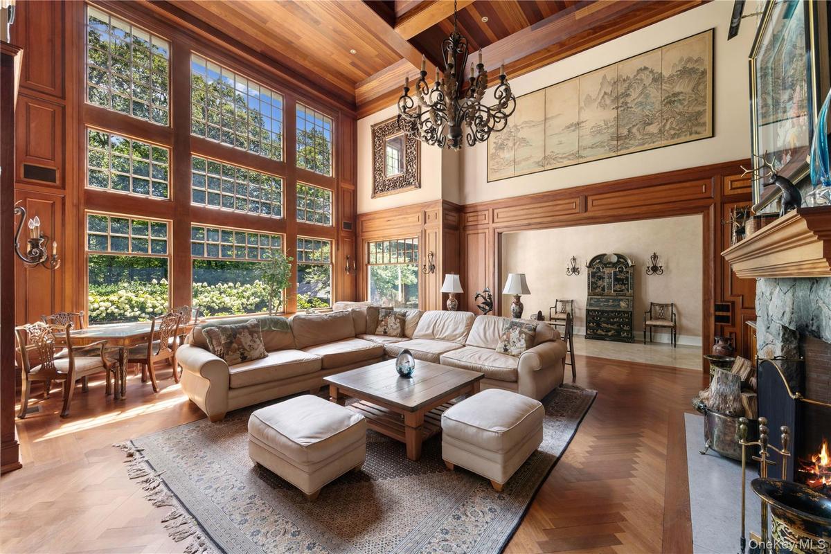 Living room with a fireplace, a wood ceiling with exposed beams, a towering ceiling, and a chandelier