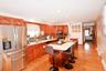 Open-concept kitchen featuring wood-finish cabinetry, stainless steel appliances, a center island with countertop seating, and wood-finish flooring