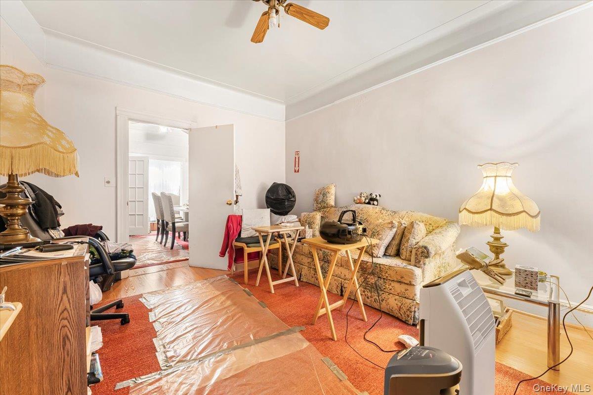 Office area with a ceiling fan, crown molding, and wood finished floors