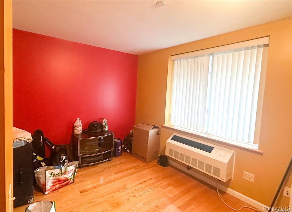 Bedroom with light wood-style floors and a wall unit AC