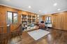 Home Office – Spacious home office showcasing rich hardwood flooring, recessed lighting, and multiple windows that fill the room with natural light. D