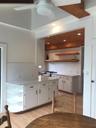 Kitchen featuring white cabinets, backsplash, light wood finished floors, and open shelves