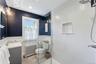 Bathroom featuring a shower stall, vanity, radiator heating unit, a wainscoted wall, and recessed lighting
