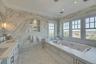 Bathroom with tile walls, ornamental molding, a whirlpool tub, double vanity, and recessed lighting