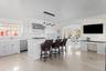 Kitchen with white cabinets, decorative light fixtures, a center island with sink, arched walkways, and a breakfast bar area