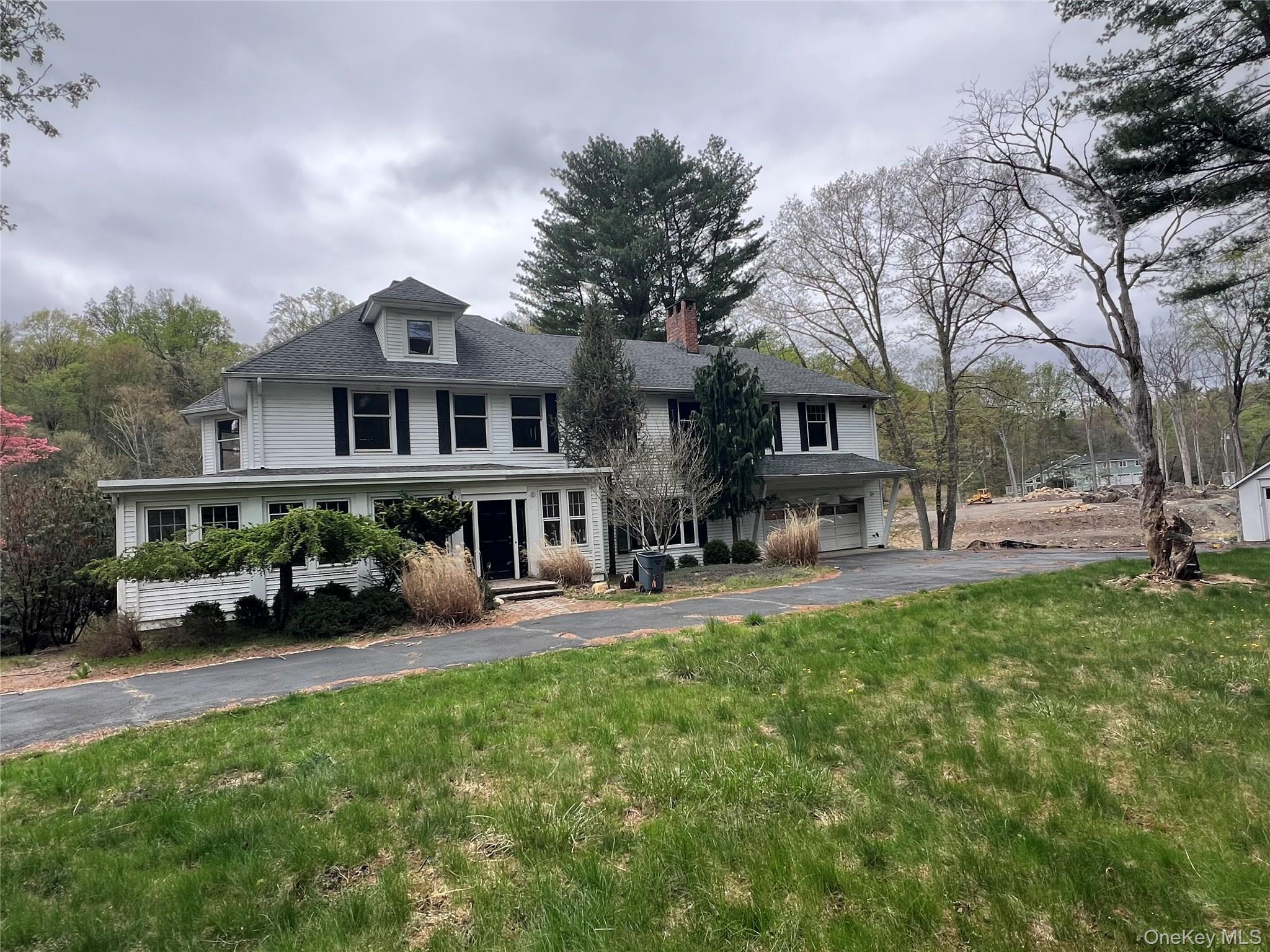 View of front of property with a front yard, driveway, an attached garage, and a chimney