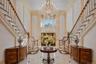 Grand foyer featuring a dual staircase with wood handrails, a large multi-tiered chandelier, and polished tile flooring with contrasting accents
