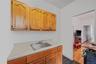 Kitchen featuring light countertops, dark wood-style floors, black gas range oven, and brown cabinetry