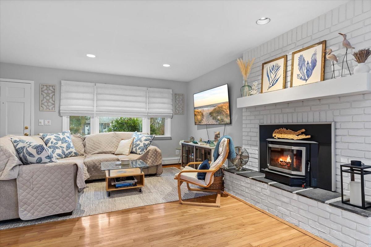 Living area featuring recessed lighting, wood finished floors, a brick fireplace, and baseboard heating