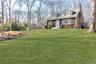 View of front of house featuring roof with shingles, a chimney, a front yard, and fence