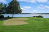 View of home's community with a water view, a putting green, and a lawn