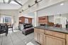Kitchen with light brown cabinetry, dark stone countertops, light tile patterned floors, open floor plan, and a skylight