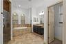 En suite primary bathroom with double sinks, walk in shower, and garden tub