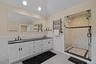 Bathroom with tile walls, a stall shower, double vanity, wainscoting, and a towel warming rack