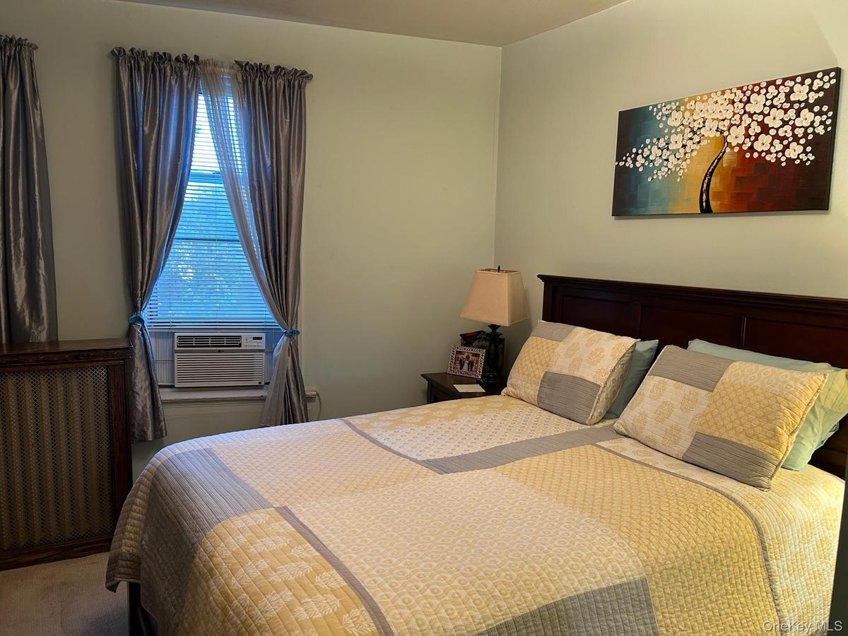 Carpeted bedroom with radiator heating unit and cooling unit