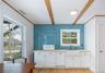Kitchen with white cabinets, white microwave, light wood finished floors, beam ceiling, and crown molding