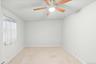 Spare room with light colored carpet, a baseboard heating unit, and a ceiling fan