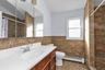 Bathroom featuring tiled shower, tile walls, a baseboard radiator, vanity, and a wainscoted wall