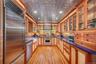 Kitchen featuring premium appliances, glass insert cabinets, recessed lighting, light wood-type flooring, and an ornate ceiling