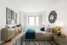 Hardwood-style flooring extends throughout this room, complemented by a large window with white draperies, a built-in radiator, and white walls